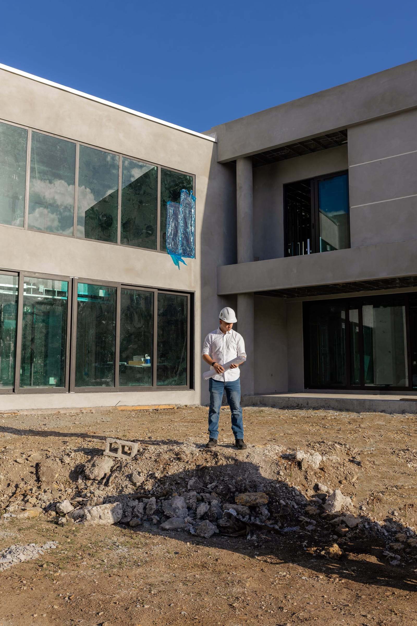 Contractor standing with plans in front of modern Florida luxury residential estate